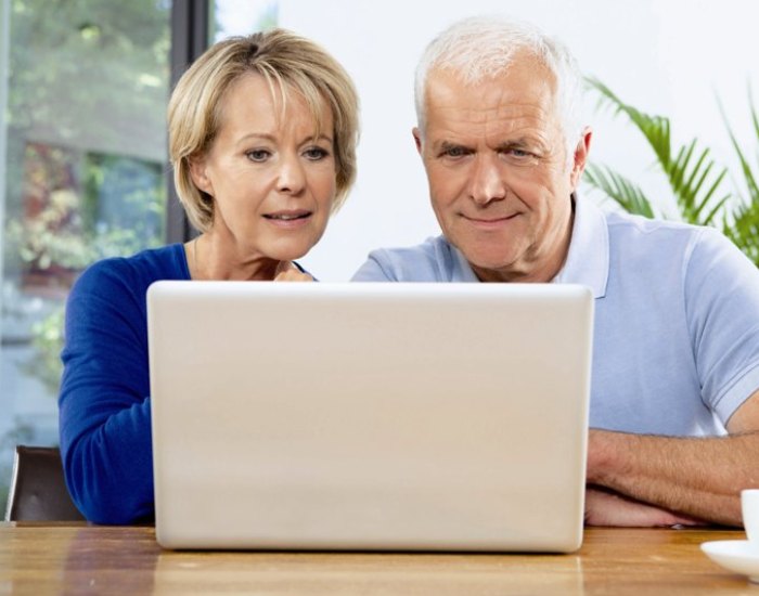 Ein älteres Paar sitzt vor dem Laptop und kann ohne Brille alles lesen